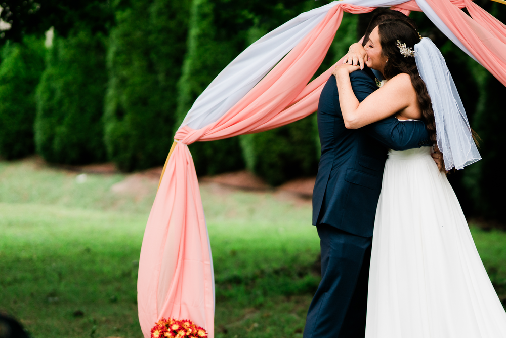 A close view of the newlyweds kissing beneath the garden arch.