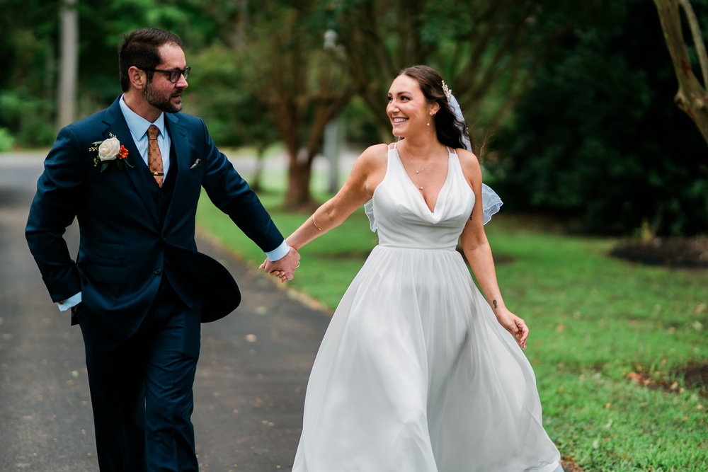 The couple walks hand in hand, smiling at one another.