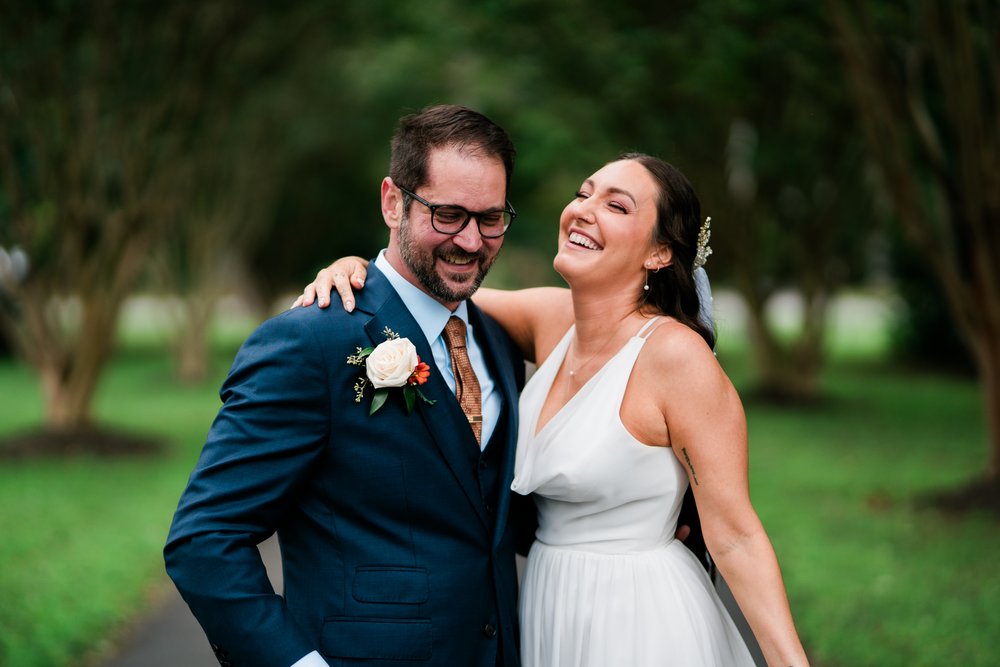 The bride and groom laugh together on the garden path.