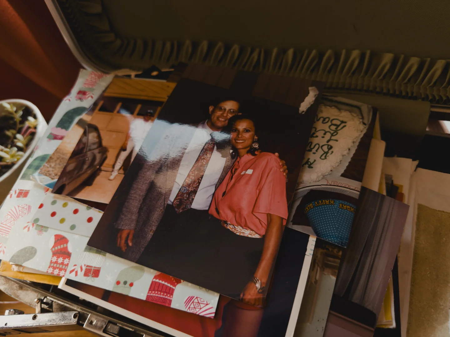 A close-up of a printed photograph of Bart’s parents smiling together, resting among the other pictures in the box.