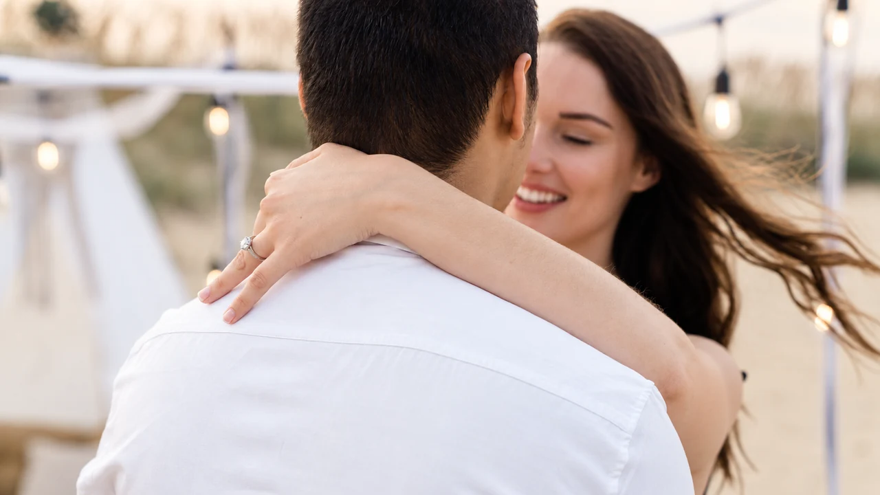 Close embrace with her face over his shoulder at the beach.