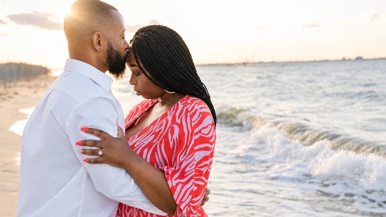 Couple embraces at the edge of the water in warm sunset light.