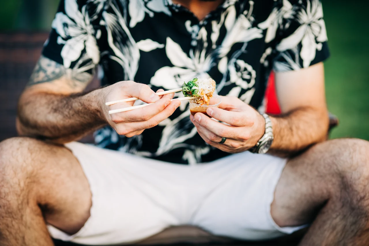 Groom holds a bite of food with chopsticks.