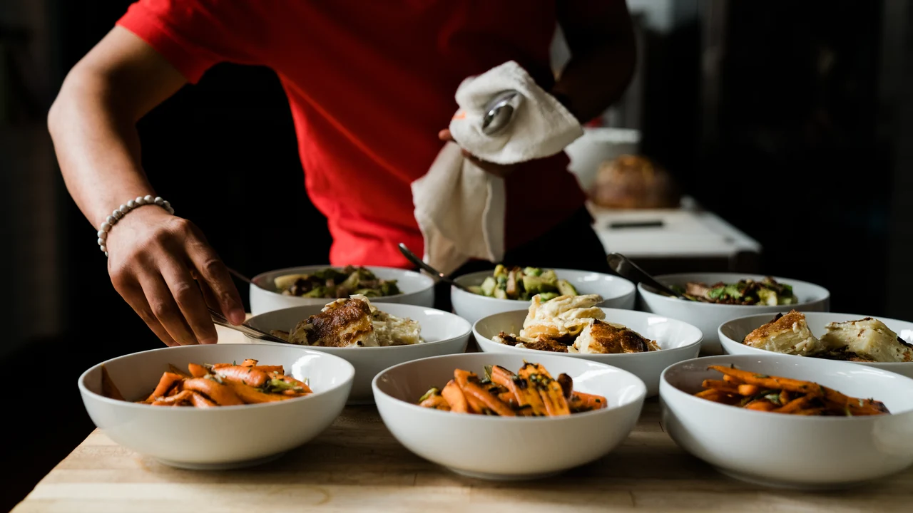 A server finishes plates of food before they are served.