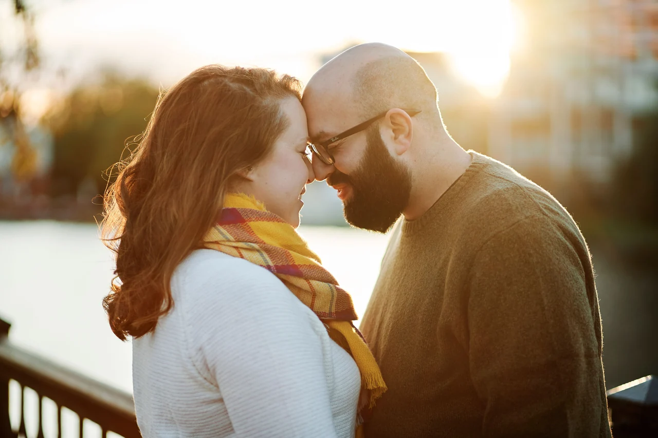 Couple rests their foreheads together outdoors in golden backlight.